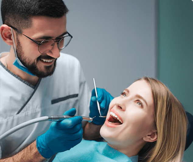 Frau sitzt beim Zahnarzt und öffnet den Mund, während ein Zahnarzt mit Brille und Handschuhen ihre Zähne untersucht und dabei lächelt.